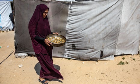 A Palestinian woman carries a tray of food in the Rafah camp in the southern Gaza Strip.