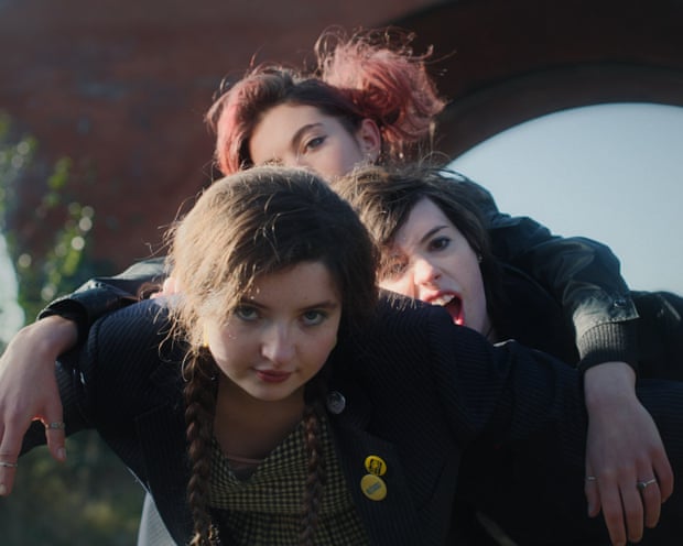Three young women pose closely together outdoors