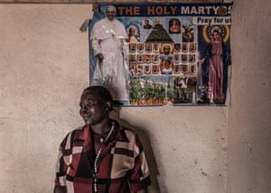 Grace Gipatho in her home with a poster showing Pope Francis behind her