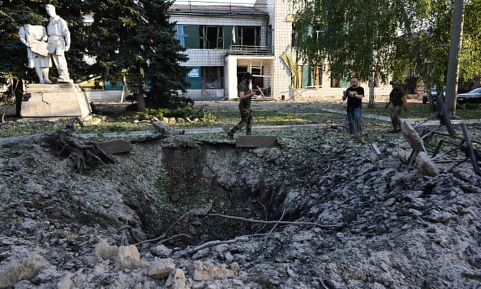 Servicemen and residents look at a crater at the House of the Culture, in Druzhkivka, eastern Ukraine, following a suspected missile attack