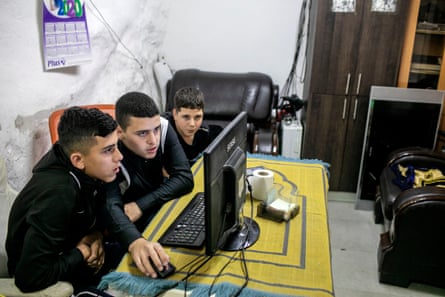 Three boys crowd around a computer screen