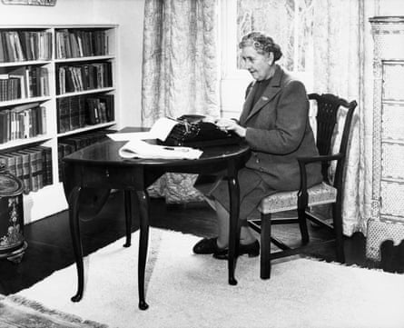 Black and white image of Agatha Christie in 1946, sitting at a table at her home and typing, with sheets of paper around her