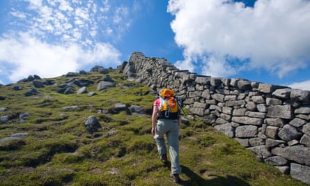 Walker beside the Mourne Wall on the ascent of Slieve Bearnagh, Mourne Mountains, County Down, Northern Ireland, UK.