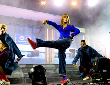 PinkPantheress does a high kick in jeans and red shoes