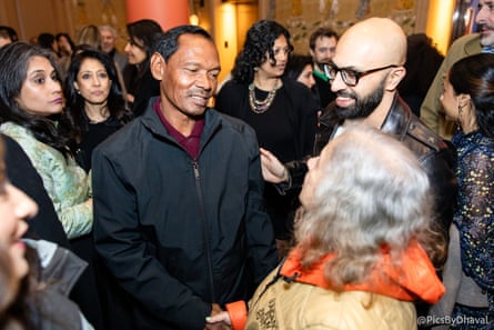 A man stands in the middle of a crowd of people shaking a woman’s hand