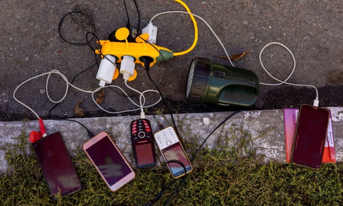 Locals charge their mobile phones with the electricity provided from a generator in front of a shop as there is no electricity in Balakliia.
