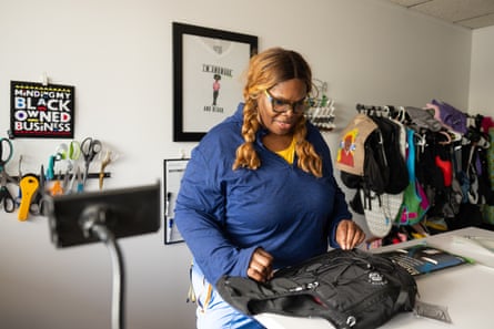 a woman looks down at a vest on a table