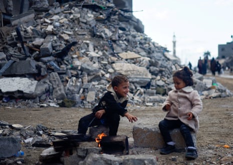 Palestinian children sit by the fire next to the rubble of a house in Khan Younis.
