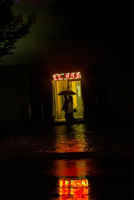 A couple in a doorway on a rainy night in Pyongyang