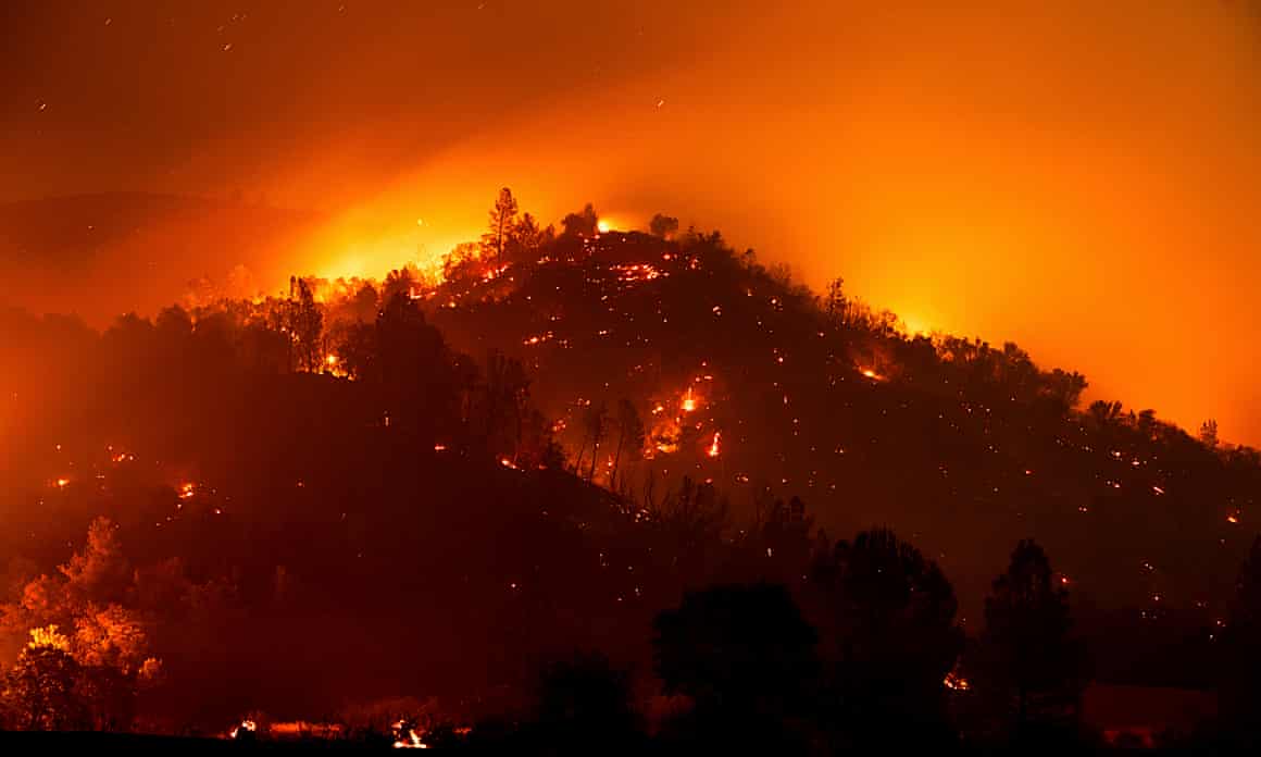 The night sky is turned orange by flames on a hillside