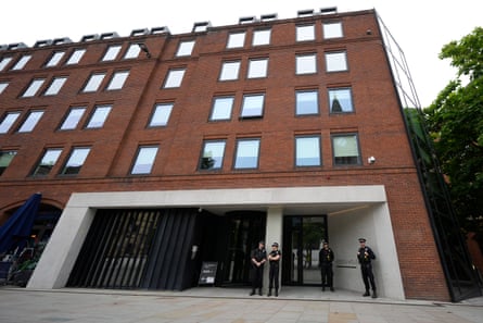 Police officers standing guard outside the entrance to Heron House, a big red brick building