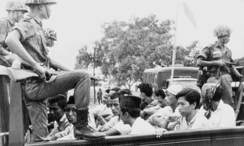 Members of the youth wing of the Indonesia Communist party (PKI) are guarded by soldiers as they are taken by open truck to prison in Jakarta, in October 1965
