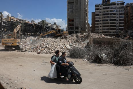 Men ride a scooter past the rubble of buildings damaged in Israeli strikes in Beirut’s southern suburbs.