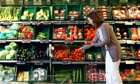 Woman shopping in a large supermarket fruit and vegetables department.