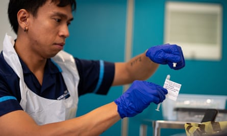 Νοσοκόμα με ποδιά και γάντια που κρατούν σύριγγα