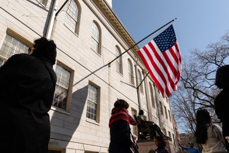 An American flag flies over a statue in front of a white building