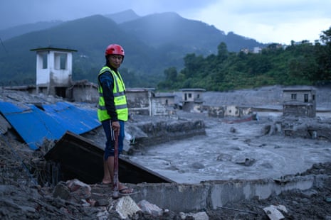 A rescuer at the site of damaged buildings at Trishuli Bazar