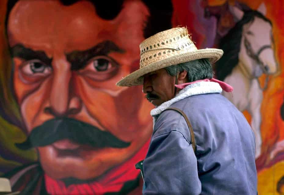A protesting farmer stands in front of a mural with the face of Emiliano Zapata in the town square of San Salvador Atenco, Mexico.
