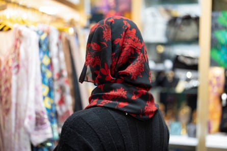 a woman wearing a floral patterned headscarf looks away from the camera