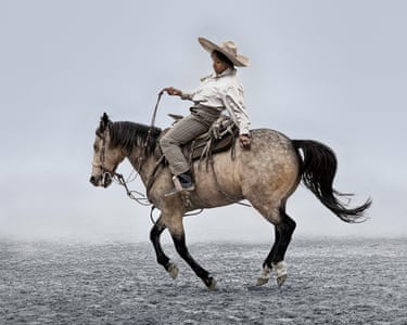 A woman dressed in masculine clothing riding a horse against a pale, misty background.