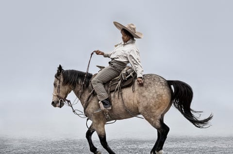 A woman dressed in masculine clothing riding a horse against a pale, misty background.