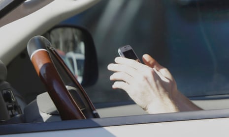 A mobile phone held by a driver at the wheel