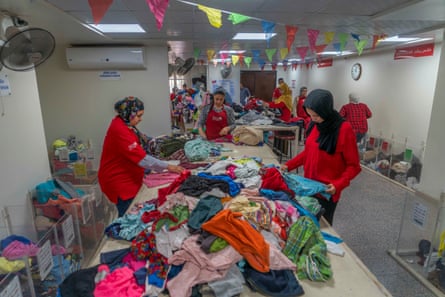 Woman in hijab sorting piles of clothes on table