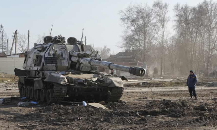 A local resident looks a damaged Russian tank in the town of Trostyanets, about 400km (250 miles) east of Kyiv.