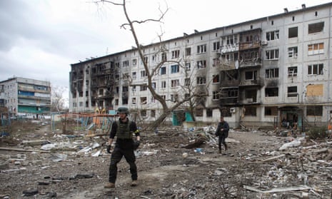 Parry and his friend Dave Young walk next to a residential building damaged by a military strike in Bakhmut.