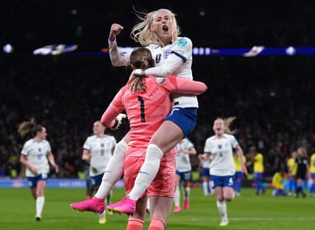 Chloe Kelly being held by Mary Earps as Kelly shouts out with her right arm in the air