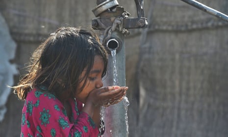 A young girl drinks water from a hand pump on a street in Lahore, Pakistan.