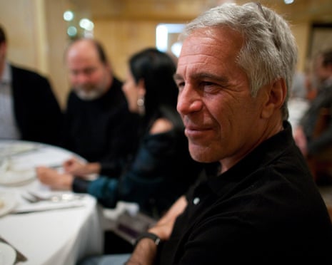 a man smiles while seated at a table