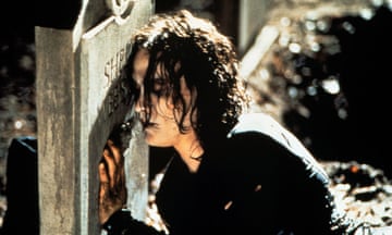 Brandon Lee as Eric Draven kneeling against a gravestone in The Crow