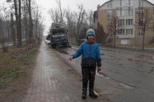 A young Ukrainian boy plays next next to destroyed Russian military machinery in the city of Bucha, Ukraine.
