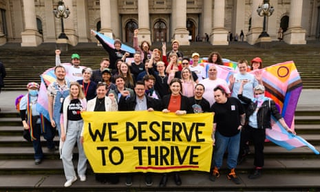 Pro LGBTQ+ advocates gather on the steps of Victorian parliament behind a banner which reads 'We deserve to thrive'