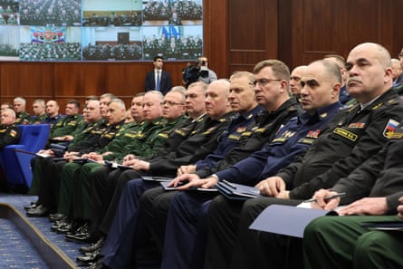 A row of stony-faced seated officials in military uniform