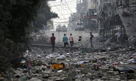 Palestinians walk among the rubble of destroyed buildings following Israeli airstrikes in Gaza City.
