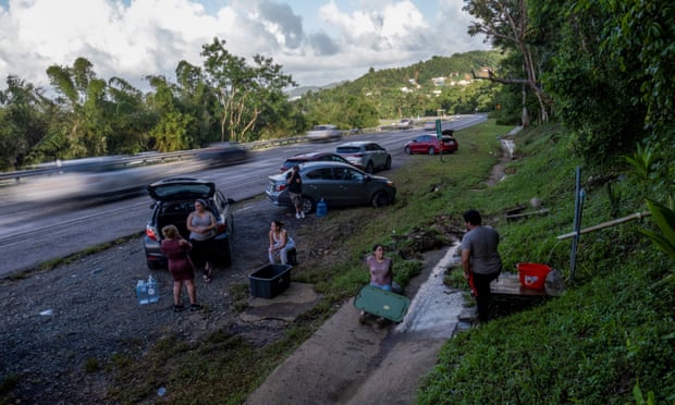 People collect spring water from a mountain next to a highway in the aftermath of Hurricane Fiona in Cayey, Puerto Rico on Wednesday.
