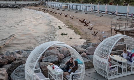 Diners sit outside a restaurant close to anti-tank blockades on a beach in Odesa, Ukraine