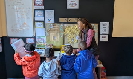 A woman at a classroom display table with four young children