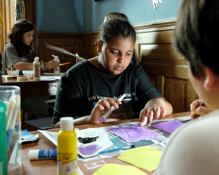 A 12-year-old girl at a table in a painting activity.