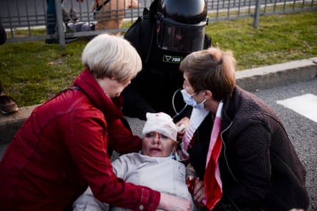 A police officer and two women help a woman injured in protests on Wednesday night in Minsk.