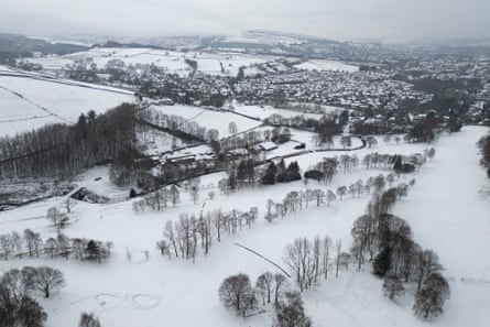 Aerial view shows a snow-covered golf course and residential properties