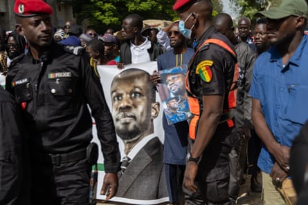 A crowd of people march holding a large poster of Senegal’s prime minister, Ousmane Sonko.