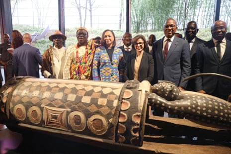 People stand behind the Djidji Ayôkwé talking drum at the Quai Branly Museum.