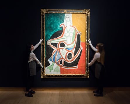 Art handlers hold up Picasso’s ‘Femme dans un rocking-chair’ in a gold frame