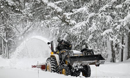A person clears snowy roads with a backhoe loader.