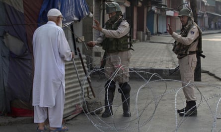 A Kashmiri man is stopped before being allowed to pass near a temporary checkpoint in Srinagar