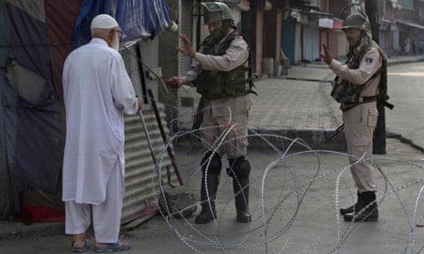Indian paramilitary soldiers stop an elderly Kashmiri man at a checkpoint in Srinagar.