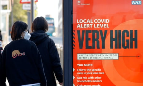 A person wearing a mask walks past a Covid warning sign in Liverpool